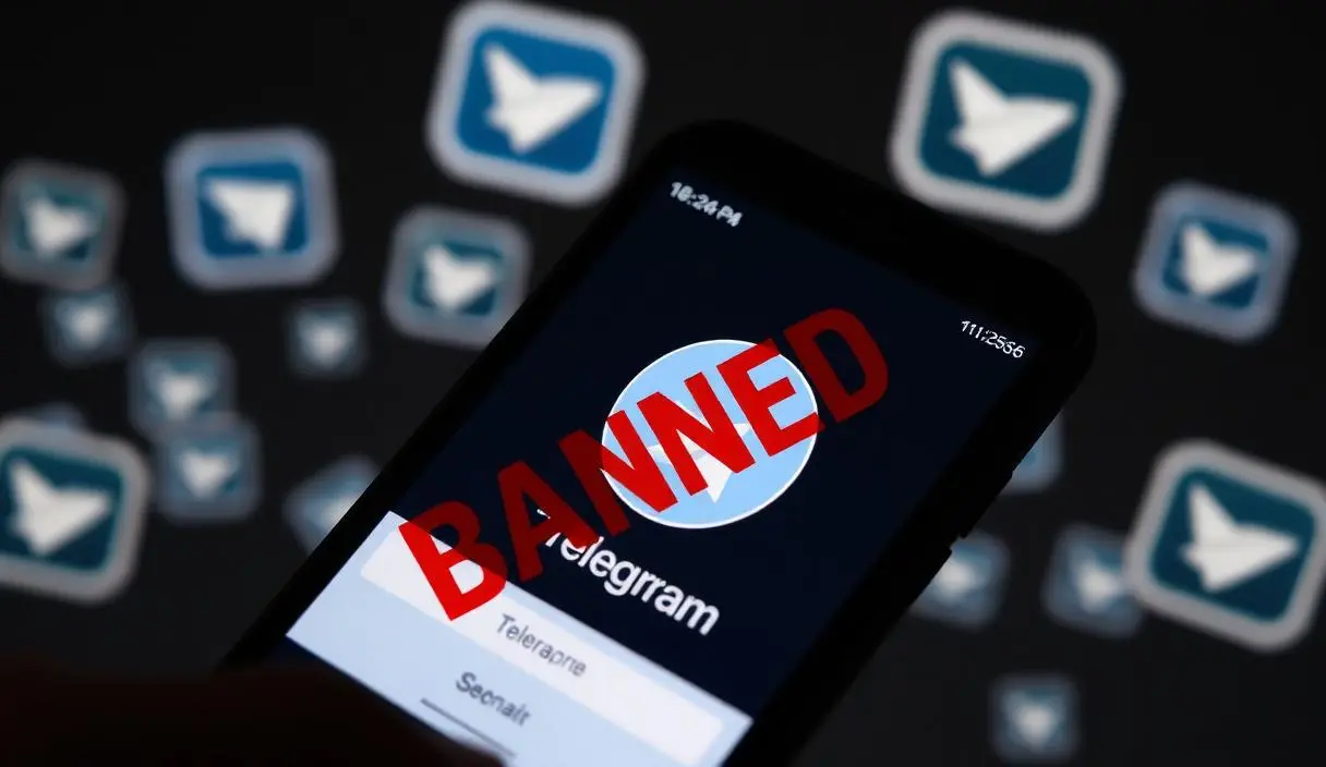 Smartphone com tela de conta Telegram banida e ícones de chat criptografado flutuando ao redor