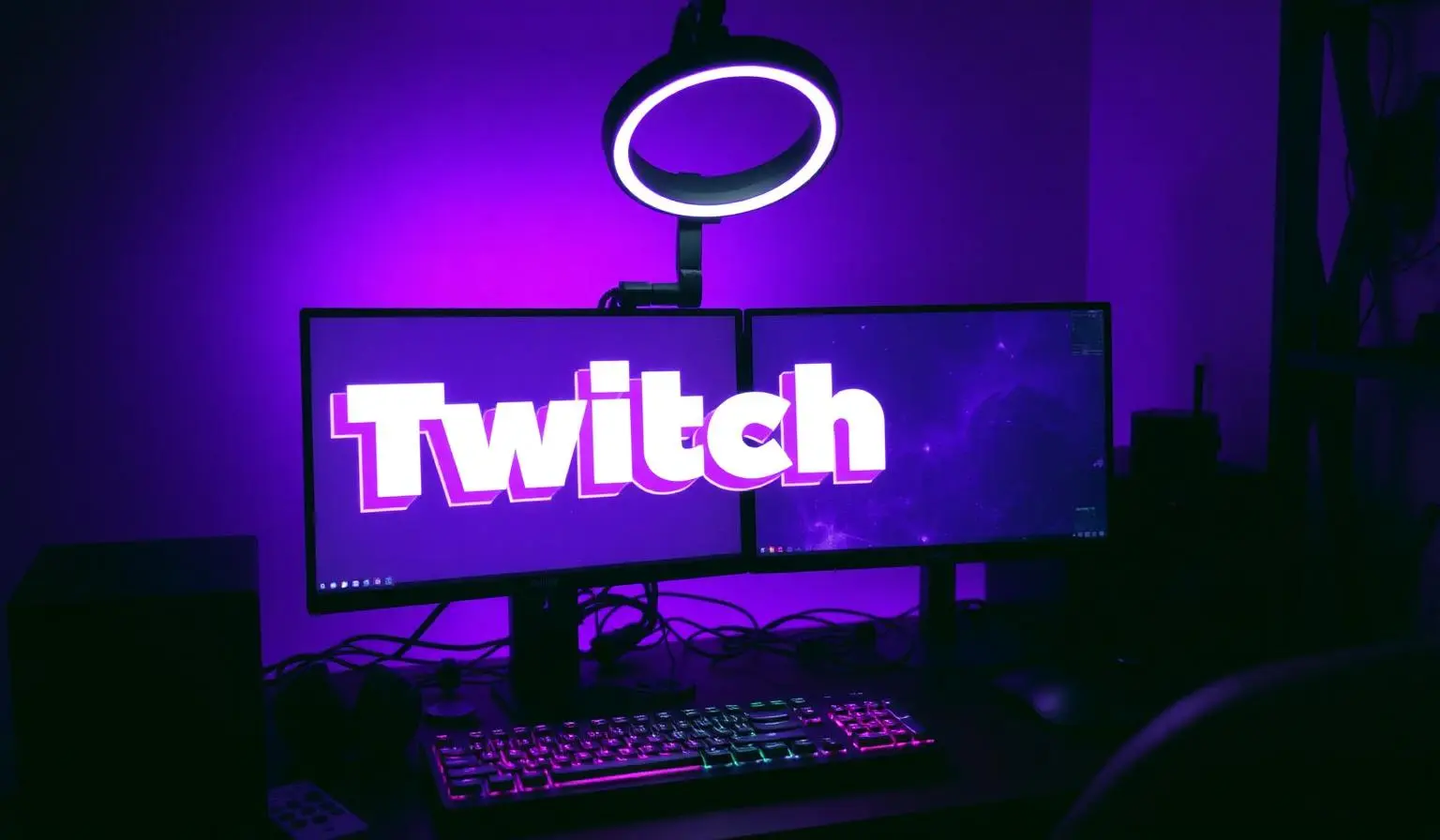 Setup de streamer com monitor exibindo logo Twitch em luz roxa neon